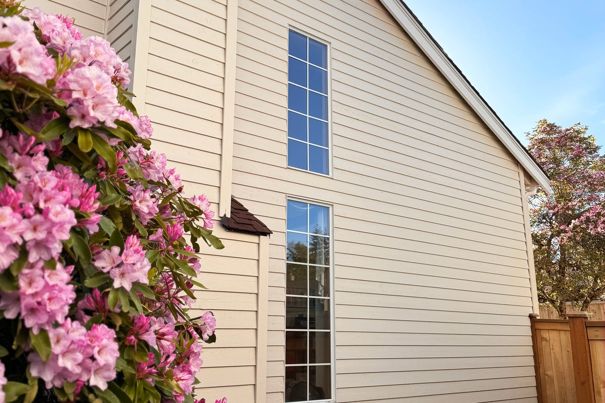 Two-story home with wood siding and a manicured front garden