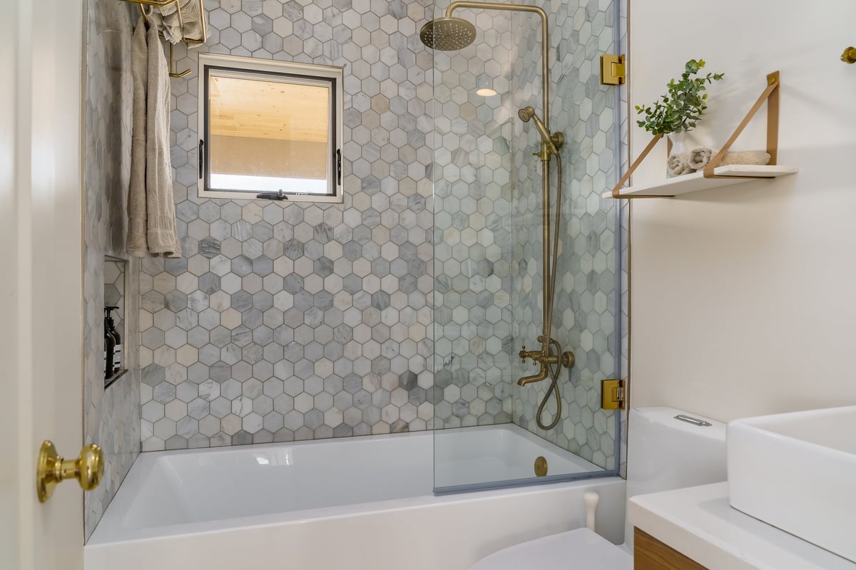 Finished bathroom remodel with white tile and gold fixtures